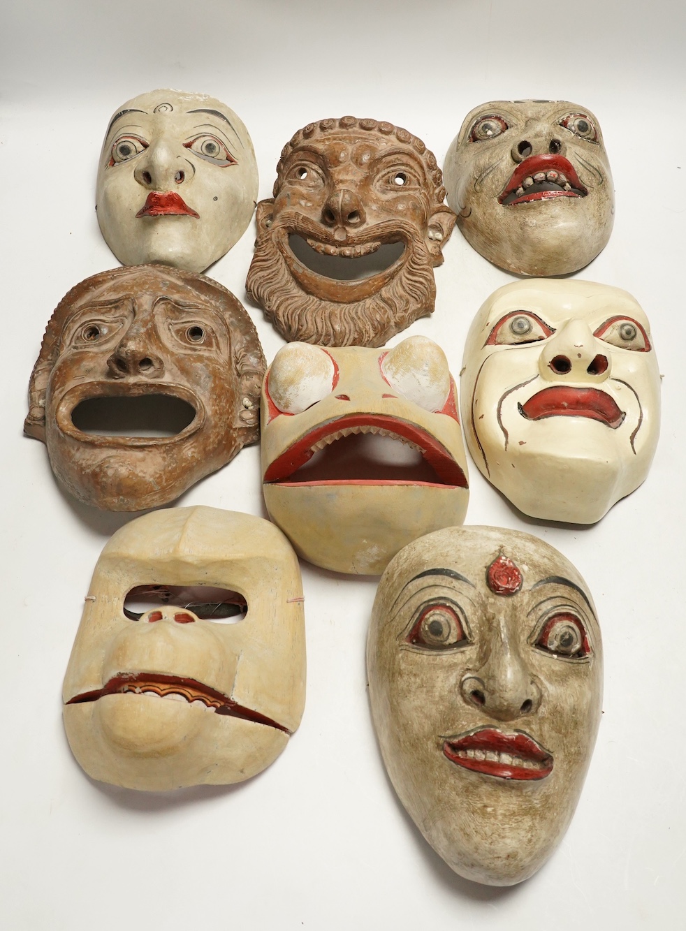 Two pottery face masks, and three pairs of carved and painted masks, largest mask 21cm high